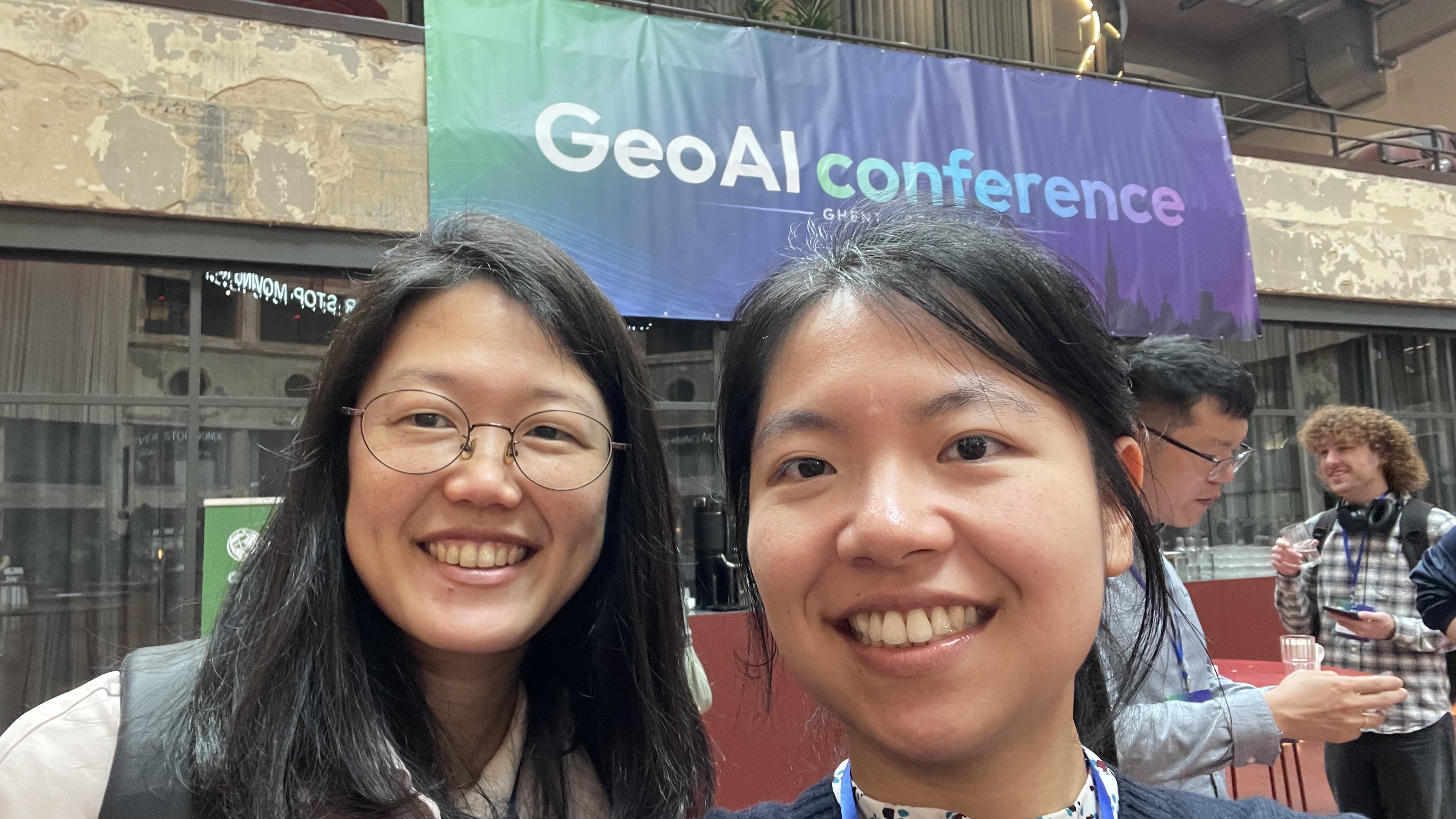 A selfie together in front of the GeoAI conference banner