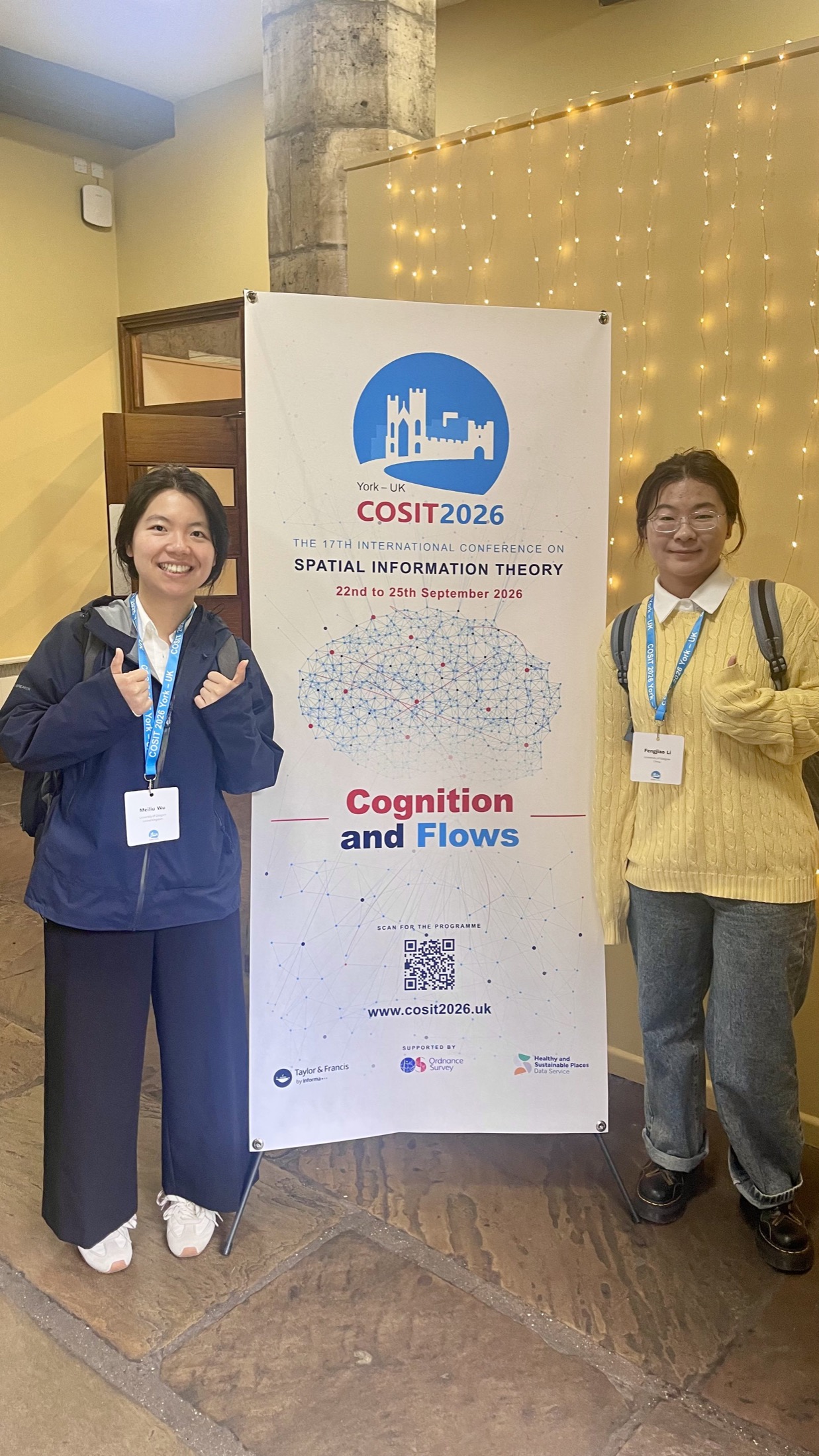 Meiliu and Fengjiao standing together beside the COSIT 2026 banner